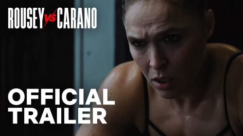 Official trailer thumbnail: close-up of a focused female fighter with sweat, overlaid with 'ROUSEY vs CARANO' and 'OFFICIAL TRAILER'.