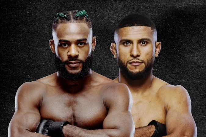 Two shirtless male boxers stand shoulder to shoulder with arms crossed, wearing gloves against a dark textured background.