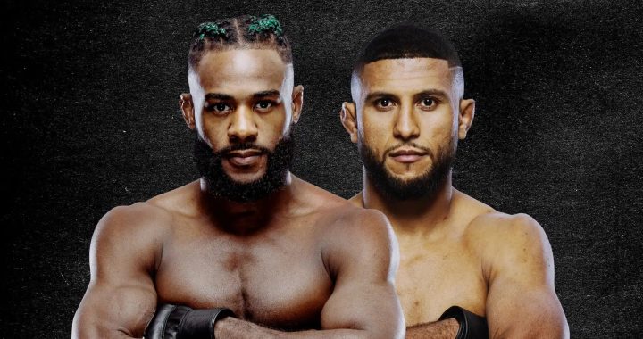 Two shirtless male boxers stand shoulder to shoulder with arms crossed, wearing gloves against a dark textured background.