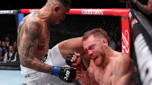 Two UFC fighters in the octagon: one lands a knee to the other's face, both battered and bleeding, with a camera crew and spectators in the background.