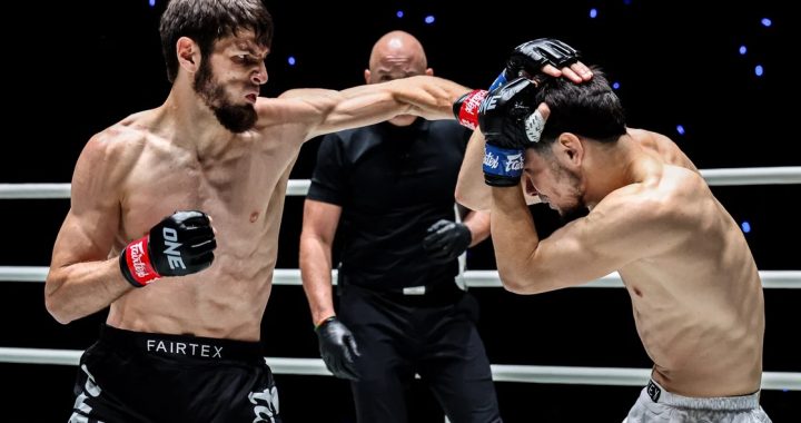 Two shirtless fighters exchange punches in a ring while a referee watches in the background.